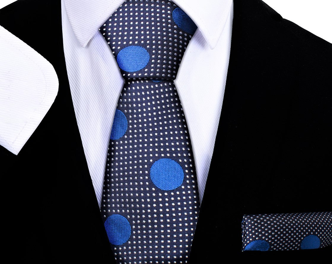 Black suit with a blue polka dot tie and matching pocket square on a white background