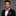 Man wearing a black suit with a red paisley bow tie and pocket square on a gray background
