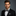 Man wearing a black suit with a patterned bow tie and pocket square on a gray background