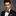 Man wearing a black suit with a blue bow tie and pocket square on a gray background