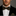 Man wearing a black suit with a patterned bow tie against a gray background