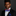 Man wearing a black suit with a red, white, and blue bow tie and pocket square on a dark background