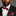 Man wearing a black suit with a red and black bow tie and pocket square against a gray background