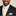 Man wearing a black suit with a beige tie and pocket square against a beige background