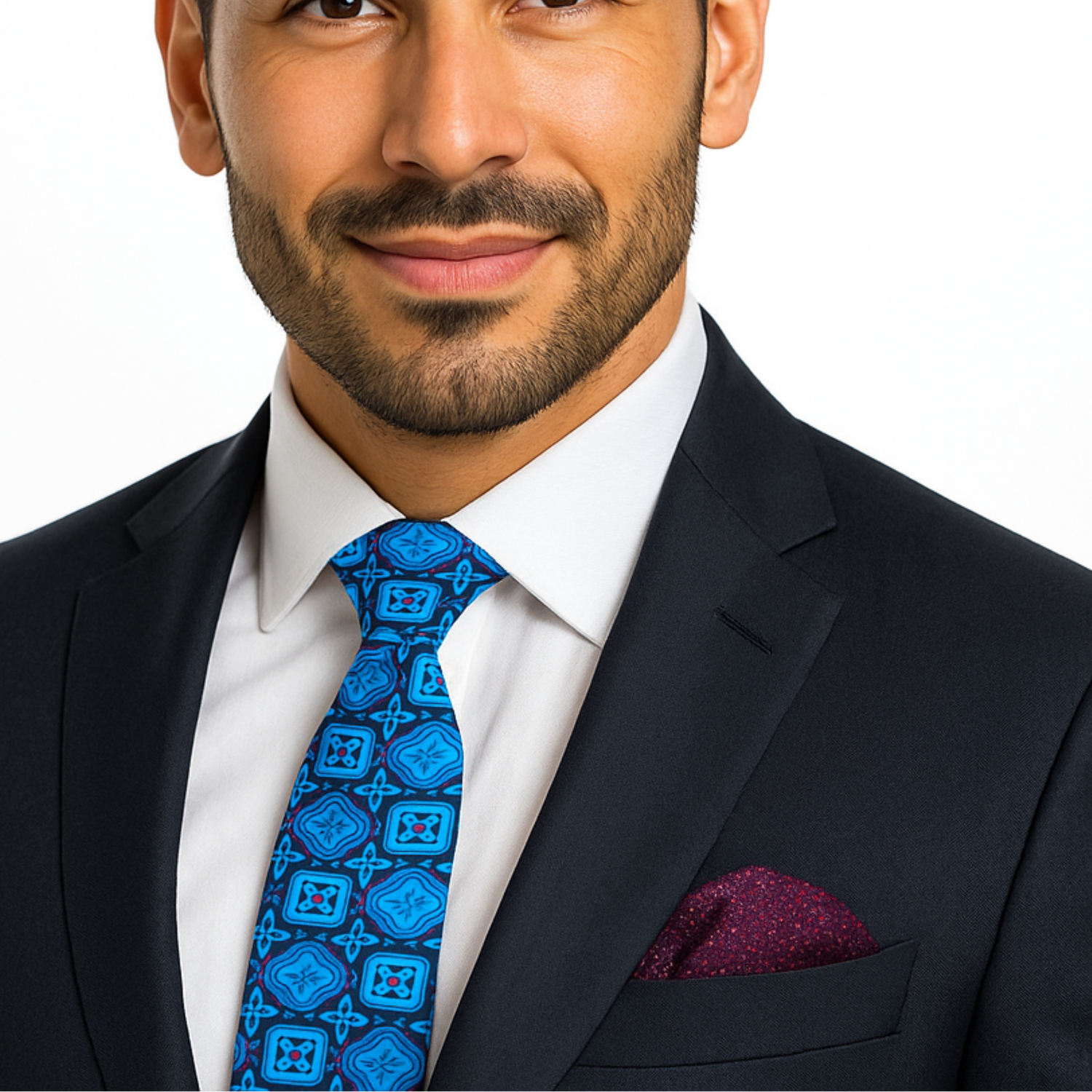 Man wearing a dark suit with a blue patterned tie and white shirt on a plain background