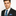 Man wearing a black suit with a blue tie and pocket square on a white background