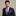 Man wearing a navy suit with a pink paisley tie and pocket square on a beige background