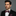 Man wearing a black suit with a red and blue striped bow tie on a gray background