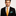 Man wearing a black suit with an orange tie and teal pocket square on a light gray background