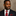 Man wearing a dark suit with a red tie and pocket square against a neutral background