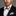 Man wearing a black suit with a white shirt and bow tie against a gray background