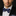 Man wearing a black suit with a white shirt and blue bow tie against a dark background