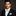 Man wearing a black tuxedo with a white bow tie and pocket square on a dark background
