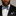 Man wearing a black suit with a blue, grey and white stripe bow tie and pocket square on a gray background