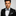 Man wearing a black tuxedo with a black and grey floral bow tie and pocket square on a gray background