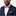 Man wearing a navy suit with a red and white bow tie on a light gray background