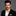 Man wearing a black suit with a gold paisley bow tie and pocket square on a gray background