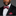 Man wearing a black suit with a red and black floral bow tie and pocket square on a gray background