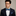 Man wearing a navy suit with a colorful blue and green stripe bow tie and pocket square against a neutral background