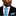 Man wearing a black suit with a blue and white striped tie and pocket square on a white background