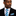 Man wearing a black suit with a blue and white striped tie and pocket square on a white background