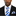 Man wearing a black suit with a blue and white striped tie and pocket square on a white background
