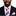 Man wearing a black suit with a red, white, and blue striped tie and pocket square on a white background