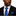 Man wearing a black suit with a blue striped tie and pocket square on a white background