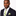 Man wearing a dark suit with a colorful white, green and yellow polka tie and pocket square on a white background