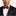 Man wearing a black suit with a red and deep blue polka geometric bow tie and pocket square on a white background