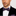 Man wearing a black suit with a white shirt and purple geometric and white polka bow tie on a light gray background