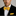 Man wearing a black suit with a yellow bow tie and pocket square against a gray background