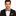 Man wearing a black suit with a red and white striped bow tie and pocket square on a white background