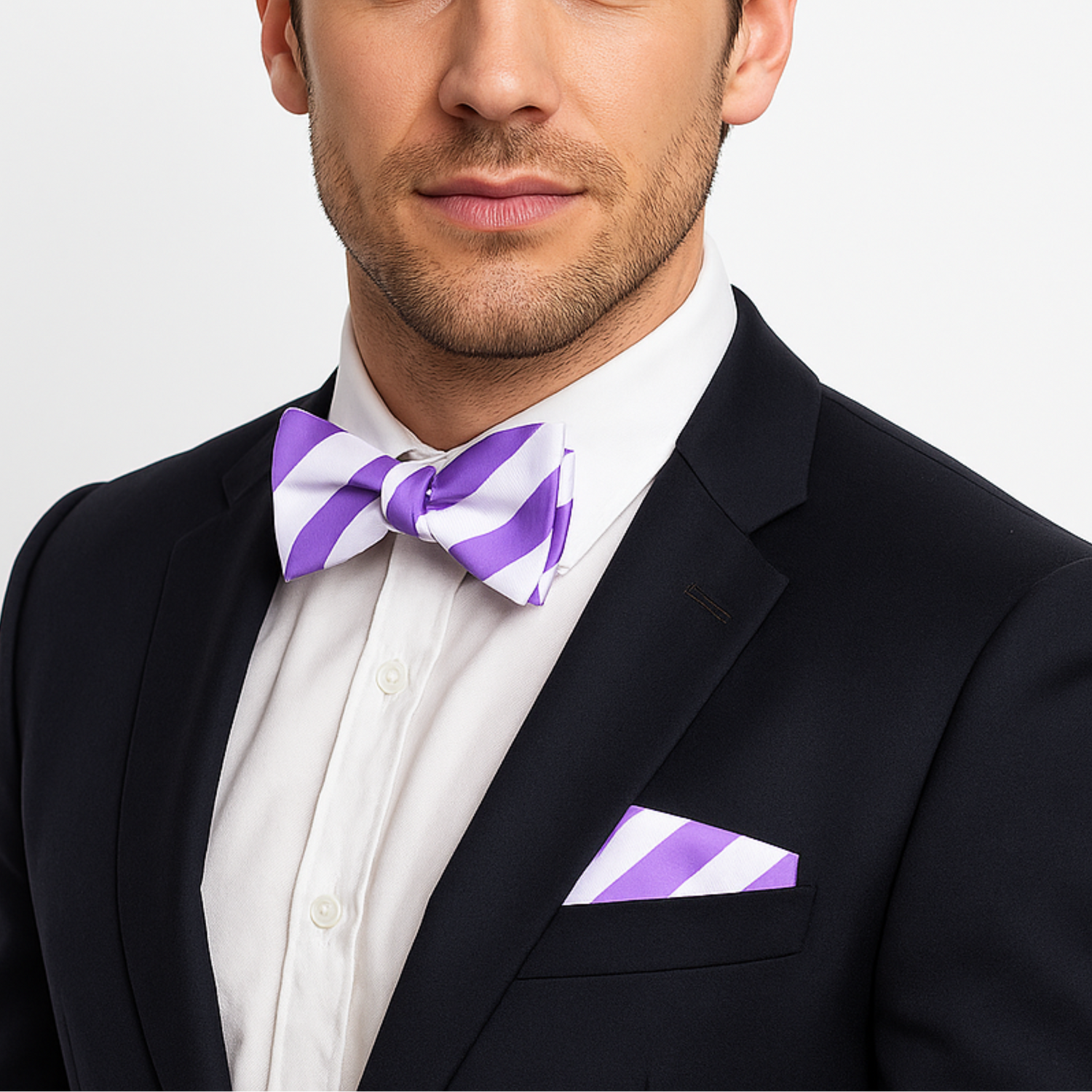 Man wearing a black suit with a white shirt and purple striped bow tie and pocket square.