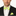 Man wearing a black suit with a white shirt, green striped bow tie, and matching pocket square on a white background.