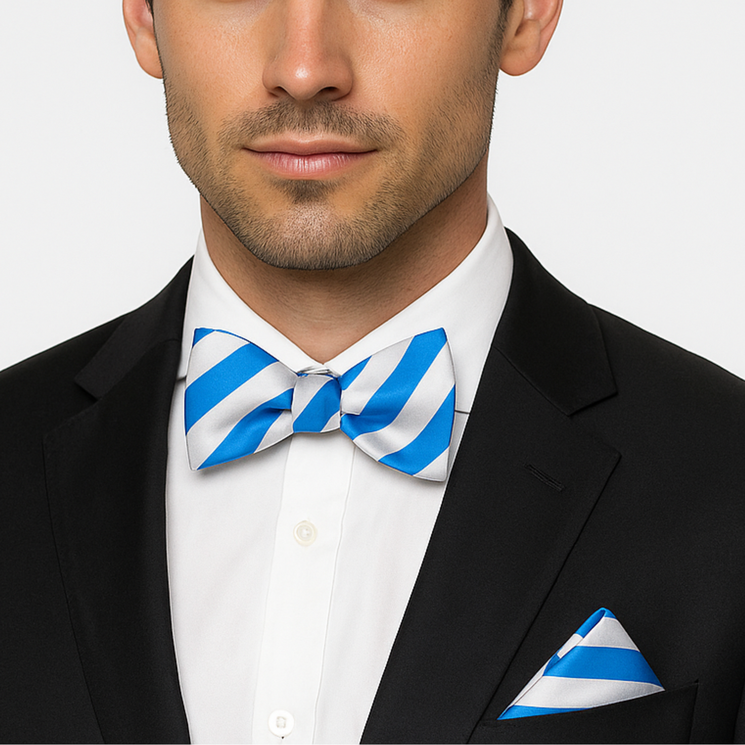 Man wearing a black suit with a blue and white striped bow tie and pocket square on a light gray background