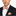 Man wearing a black suit with an orange and white striped bow tie and pocket square on a white background
