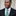 Man wearing black suit with green striped tie and black and white dot polka square