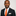 Man wearing a black suit with an orange tie and accenting pearl square on a light gray background
