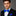 Man wearing a black suit with a blue bow tie and pocket square on a gray background