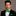 Man wearing a black suit with a green bow tie and pocket square on a gray background
