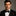 Man wearing a black tuxedo with a bow tie against a gray background