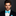 Man wearing a black suit with a white shirt and blue bow tie against a dark background