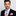 Man wearing a suit with a pink and gray striped tie and pocket square on a light gray background