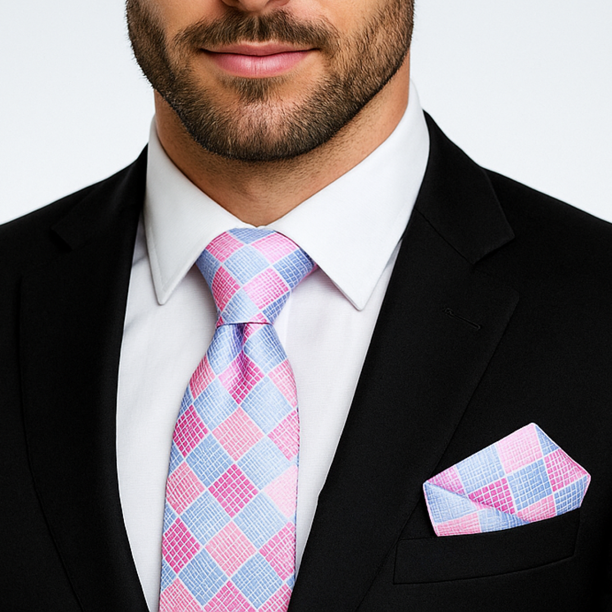 Man wearing a black suit with a pink and blue checkered tie and pocket square.