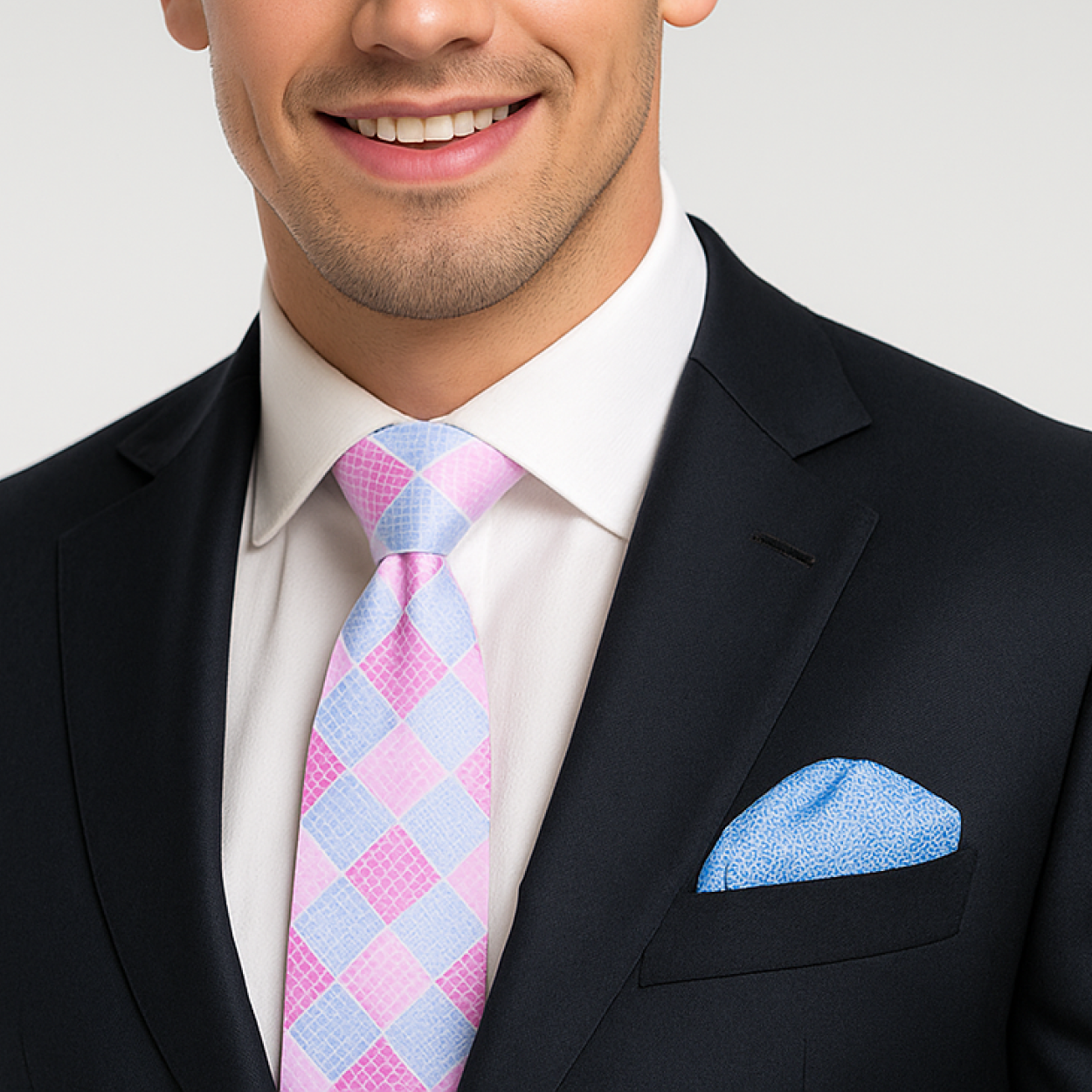 Man wearing a black suit with a pink and blue checkered tie and accenting blue pocket square.