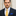 Man wearing a navy suit with a yellow tie and blue pocket square against a neutral background