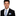 Man wearing a black suit with a blue and yellow striped tie and pocket square on a white background