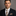 Man wearing a suit with a patterned tie and pocket square against a gray background