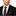 Man wearing a black suit with a white shirt and polka dot tie on a white background
